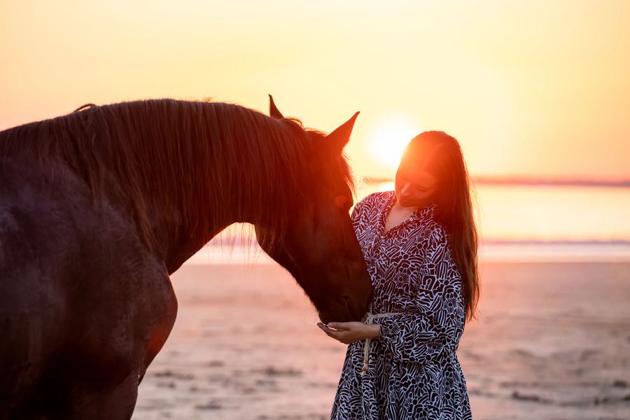 Femme et cheval au coucher du soleil