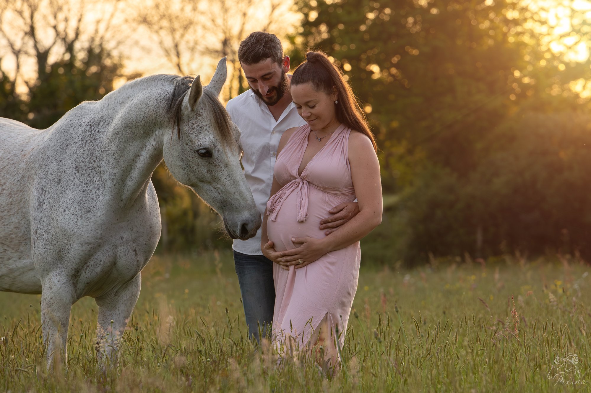 Couple attendant un enfant, entouré d'un cheval au coucher du soleil