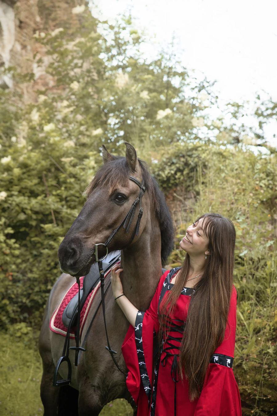 Femme en robe rouge avec son cheval