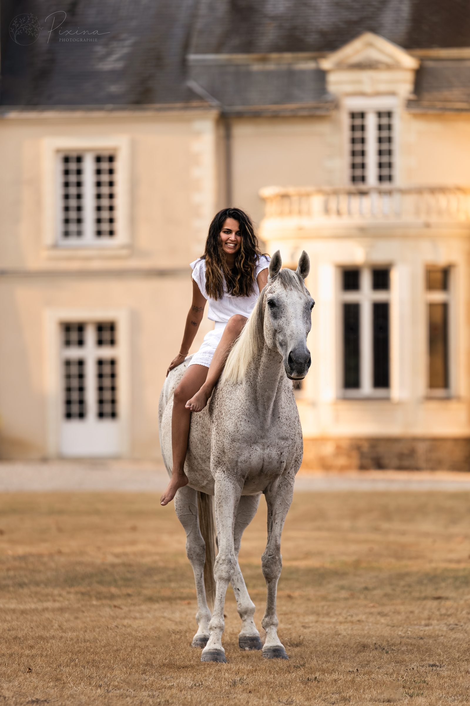Femme sur un cheval blanc devant un château