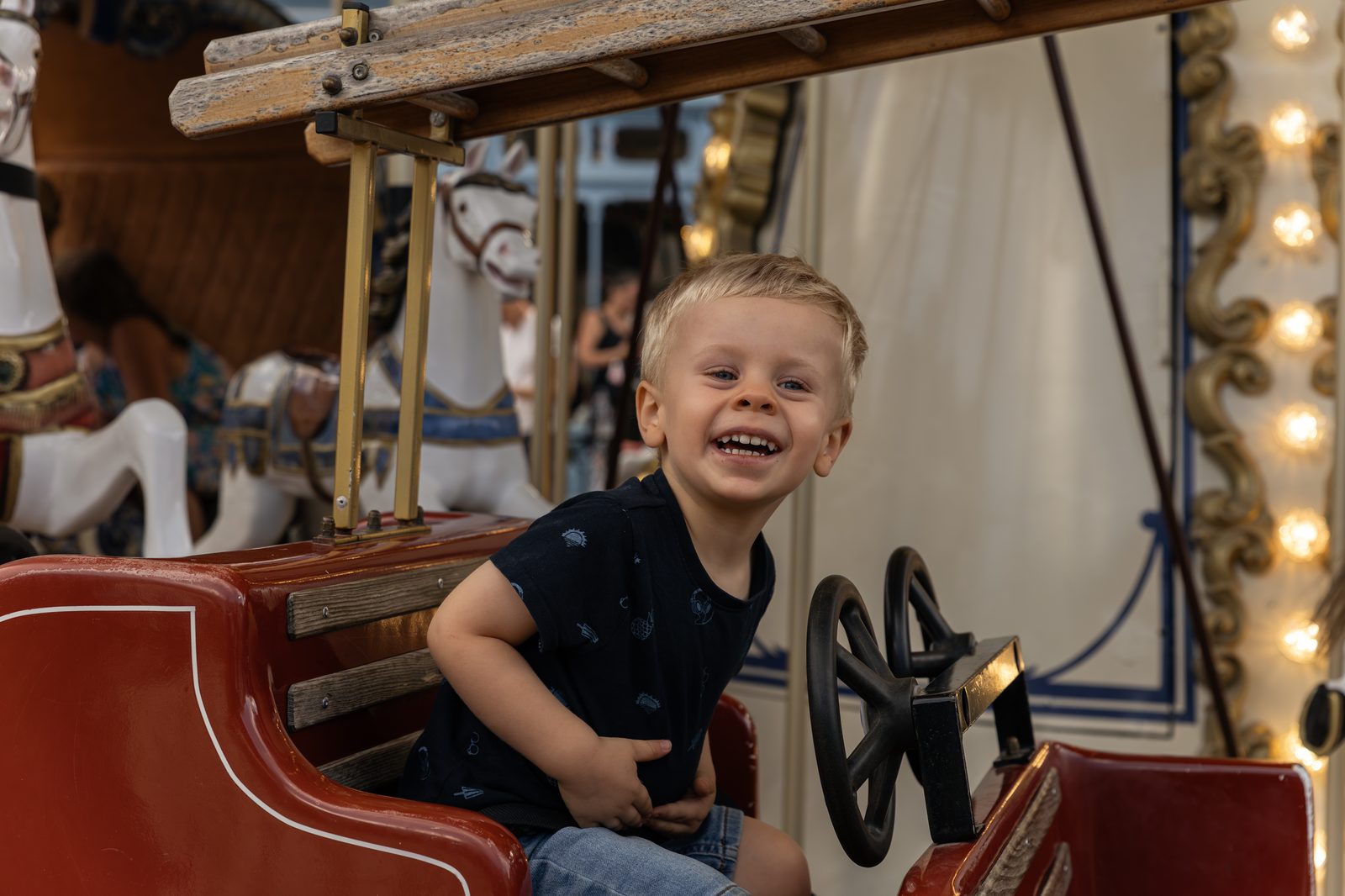 Petit garçon riant sur un manège de carrousel